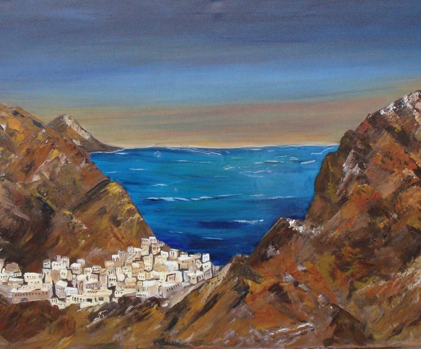 A white village between brown cliffs above a deep blue sea