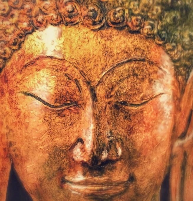 Close-up of a serene Buddha face in burnished gold and copper