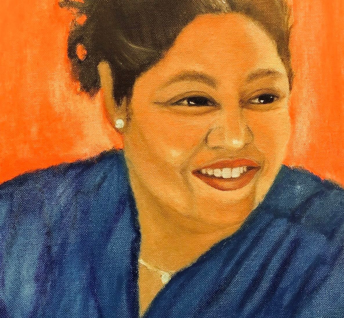 A smiling woman in a blue top against an orange background