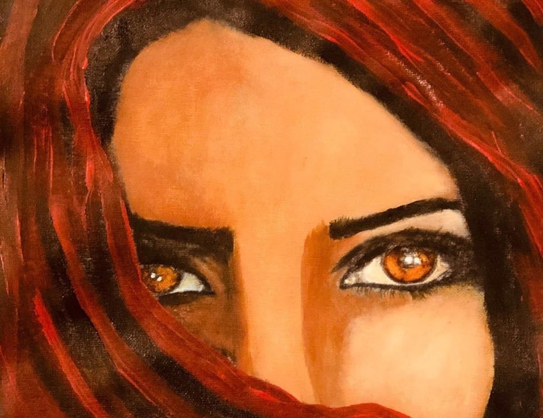 A woman’s amber eyes framed by red hair and veil