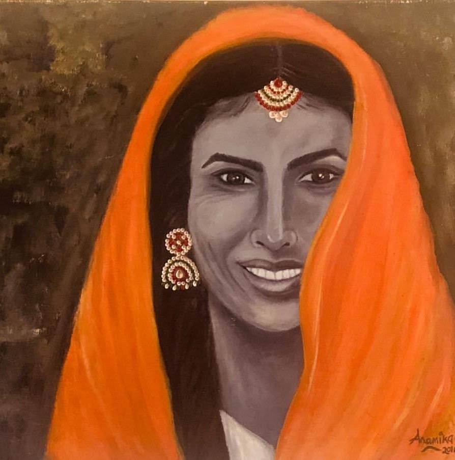 A woman in a saffron veil with a maang tikka and jhumkas