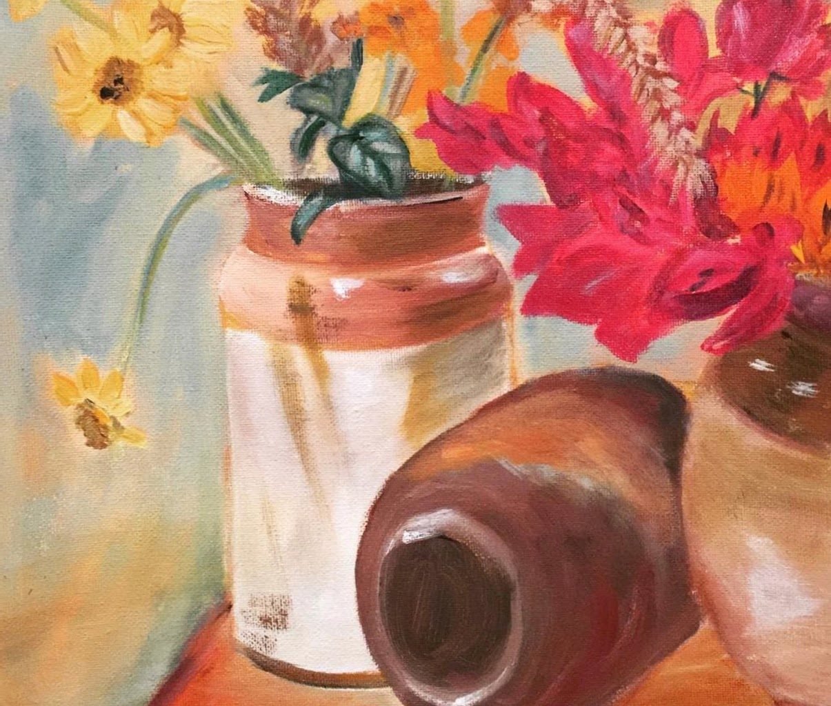 Yellow and red flowers in a jar beside an overturned clay pot